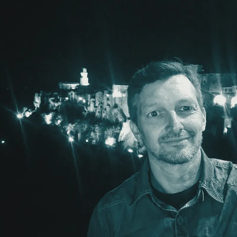 Patrizio di notte, davanti a un paese illuminato
